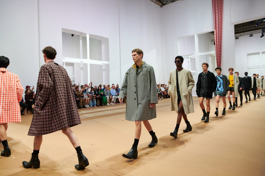 Models are pictured walking across the paper set at the Prada Spring Summer 2023 show