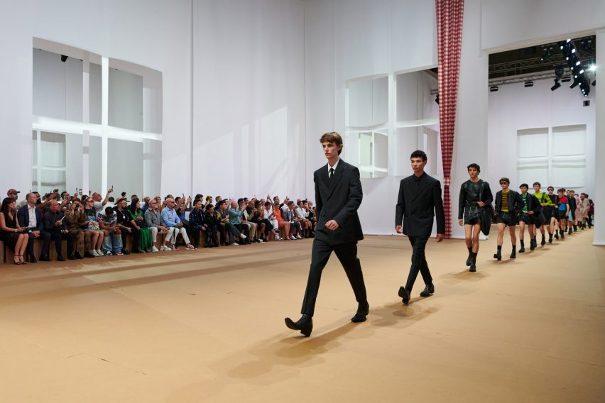 Models are pictured walking across the paper set at the Prada Spring Summer 2023 show