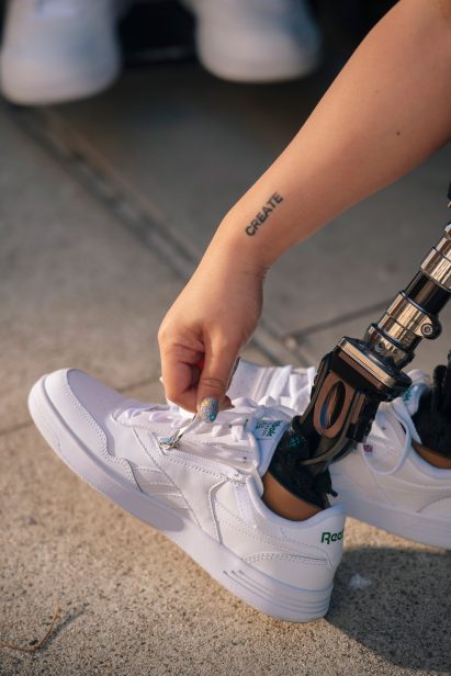 A disabled person zipping up a white pair of trainers