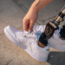 A woman zipping up a pair of Reebok trianers