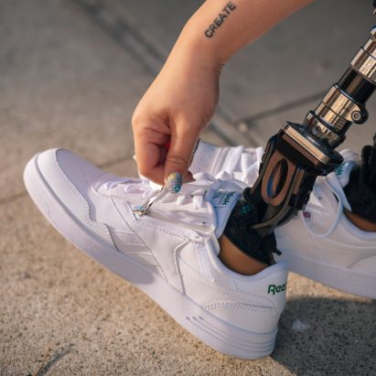 A woman zipping up a pair of Reebok trianers