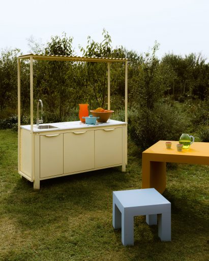 Pastel yellow kitchen unit in garden on grass lawn