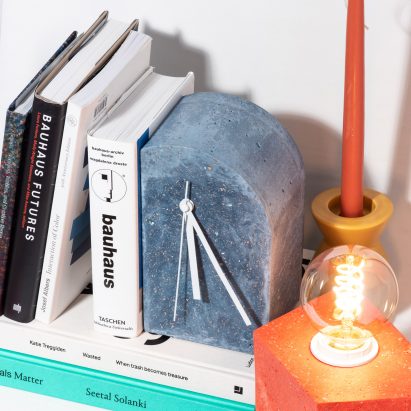Photograph showing minimal clock amongst objects on a shelf