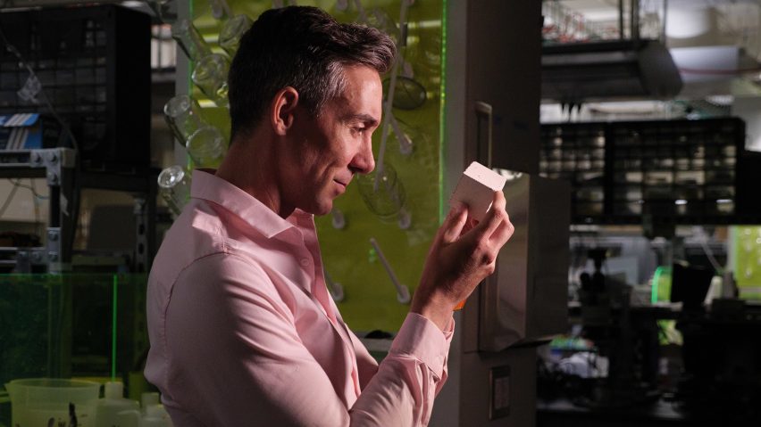 Wil Srubar holding a cube of concrete made with algae-grown limestone