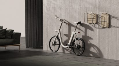 Pendler bike with pedals folded down and handlebars turned to give it a flat profile, with accessories detached and hung on the wall