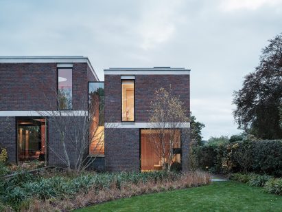 Large glass windows in brick building with glass walkway by Blee Halligan Architects