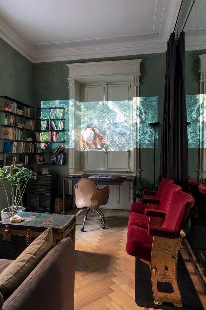 Dark interior of 02A's apartment office with a projector and cinema-themed decor