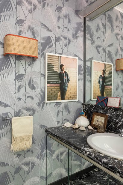 Corner of bathroom in Diplomat's House in Rome with tropical wallpaper and black marble counter