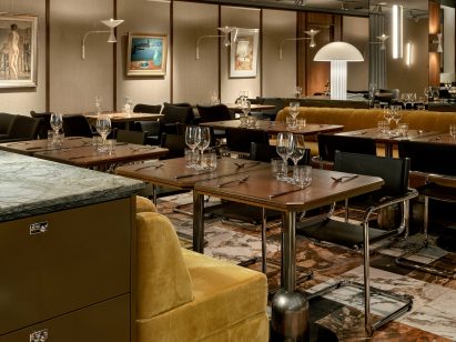 Dining set up with wooden tables and mustard yellow banquettes in OR restaurant in Hotel Torni