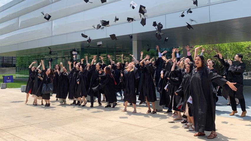 Students in graduation gowns throwing their caps in the air