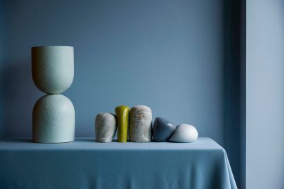 Curved blue paper lamp next to line of sculptures by Palefire Studio