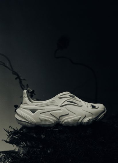 A white sandal style shoe on grassy moss