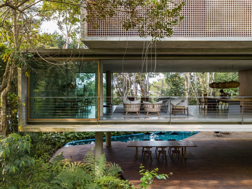 First floor of Casa Azul by Studio MK27 with open glass doors providing through views of the forest