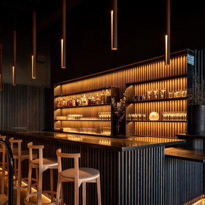 Photograph showing bar with dark wood panelling and warm lighting