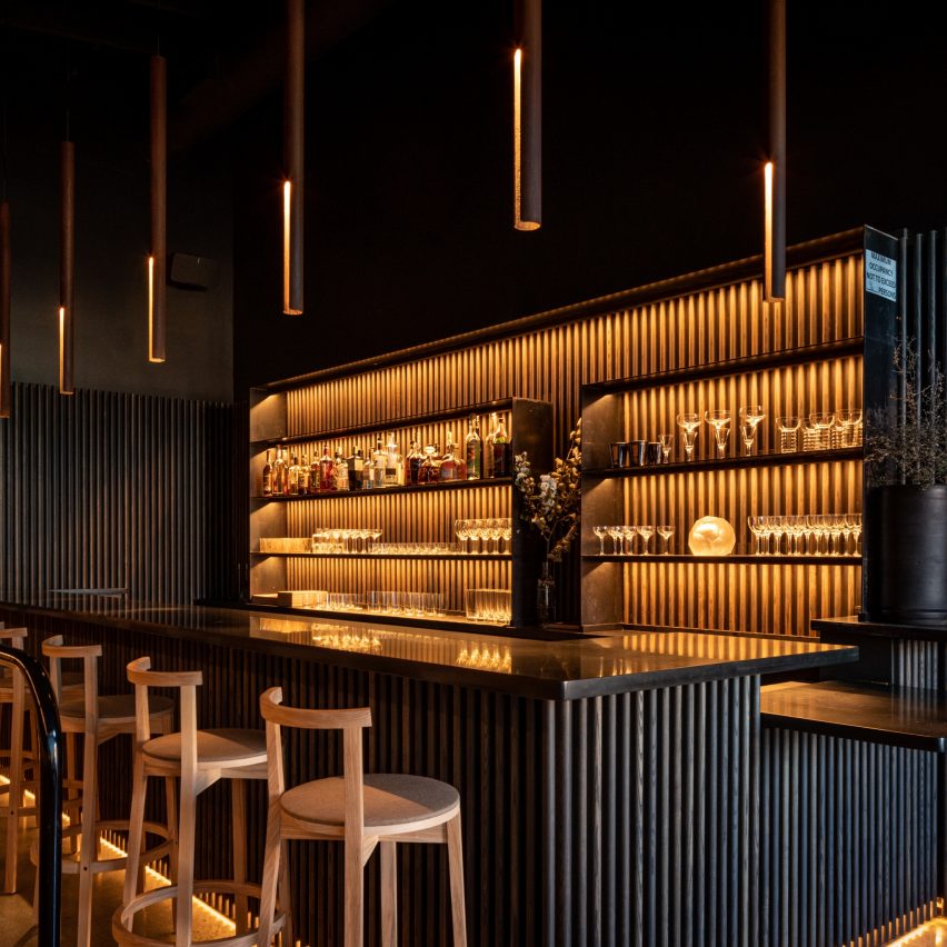 Photograph showing bar with dark wood panelling and warm lighting