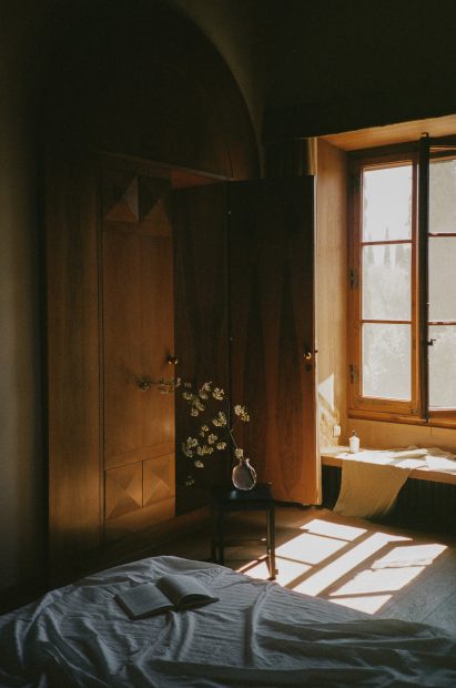 Bedroom of Albert Moya with simple bed and small stool with a plant