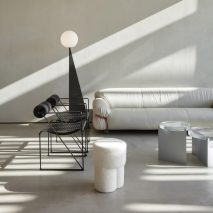 Seating area of Orijins coffee shop by VSHD Design with white couch and black metal chairs