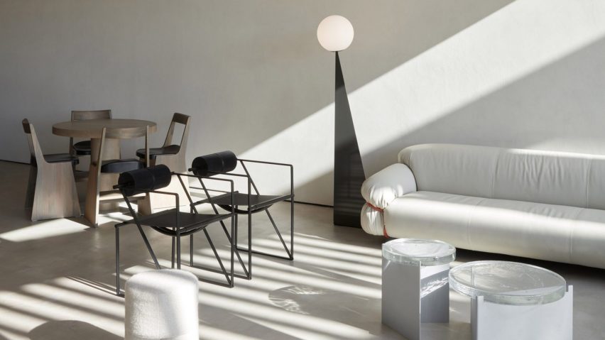 Seating area of Orijins coffee shop by VSHD Design with wooden dining table and chairs, and a white couch with black metal armchairs