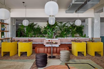 Seating area with leather banquette and yellow armchairs in Munich hotel designed by Holloway Li