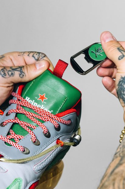 A photograph of someone holding up a bottle opener which is part of the shoe's design