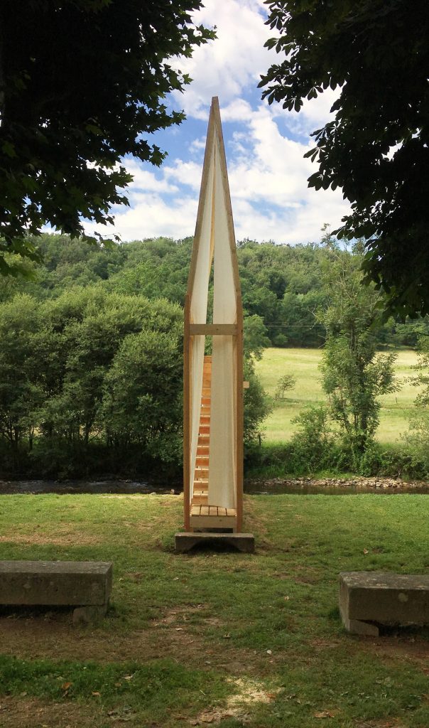 A slim wooden structure with stairs in a field