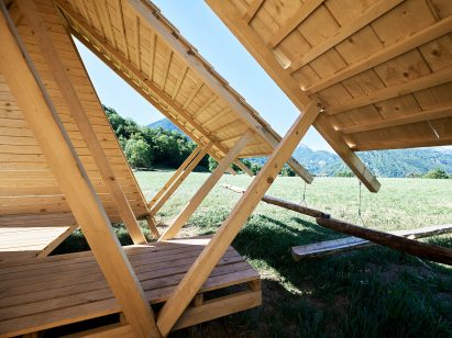A wooden hut in the middle of a field overlooking mountains