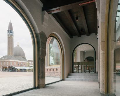 Large arched windows let light into a long white hallway