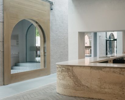 A beige reception desk sits across a wooden door frame with an arched opening