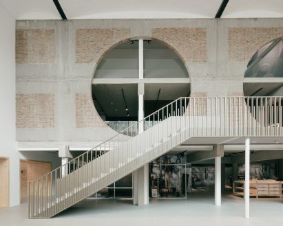 A top floor features brick walls with large round openings