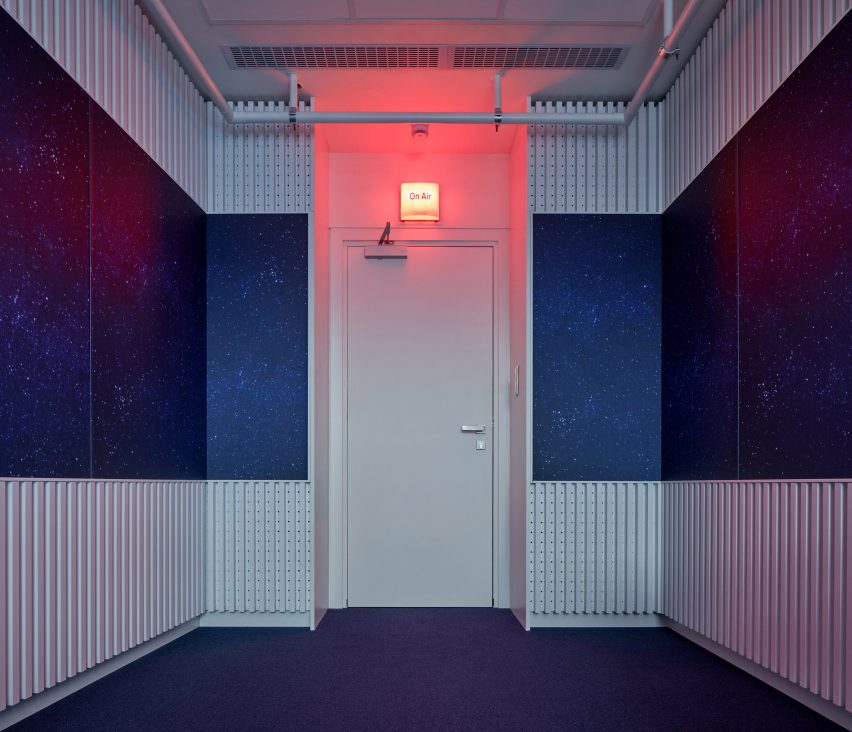 Photograph of outside of broadcasting room with red lit 'on air' sign above door