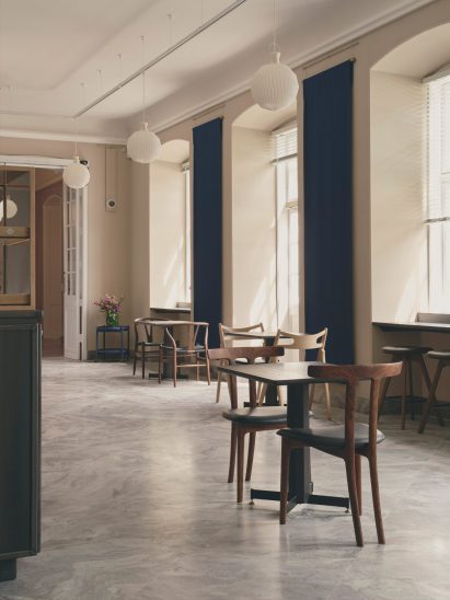 Wooden chairs stand on a stone floor inside cafe