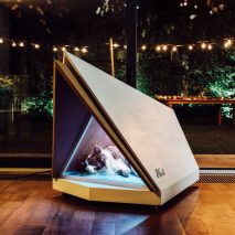 A photograph of a dog sleeping in a noise reducing kennel