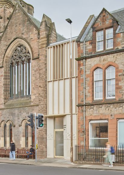 Photograph showing slim timber link building between two stone buildings