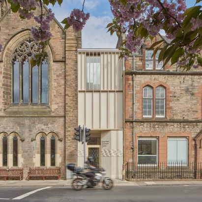 Photograph showing slim timber link building between two stone buildings