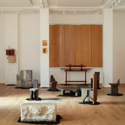 White-painted gallery with wooden floor and sculptural furniture