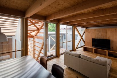Open living space with sofa and floor-to-ceiling windows in Japan by KKAA YTAA