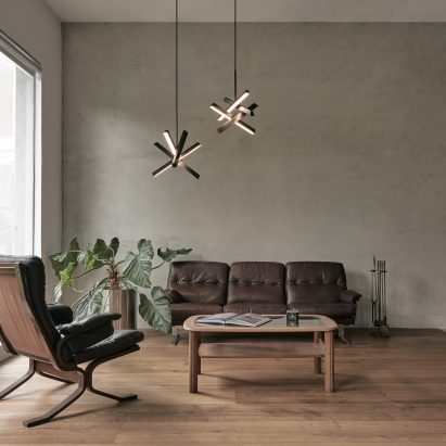 Two Konnect pendant lamps in a living room with neutral-toned walls, wooden floor and brown sofa and armchair