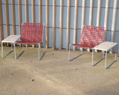 Two red lounge chairs with integrated terrazzo side tables by Local Works Studio