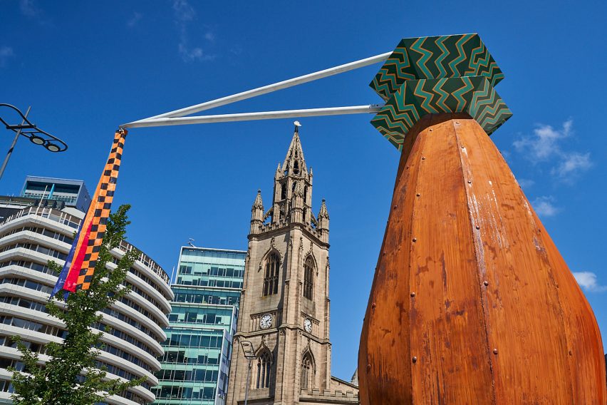 Close-up on rust-coloured Totemy sculpture topped with a green shape