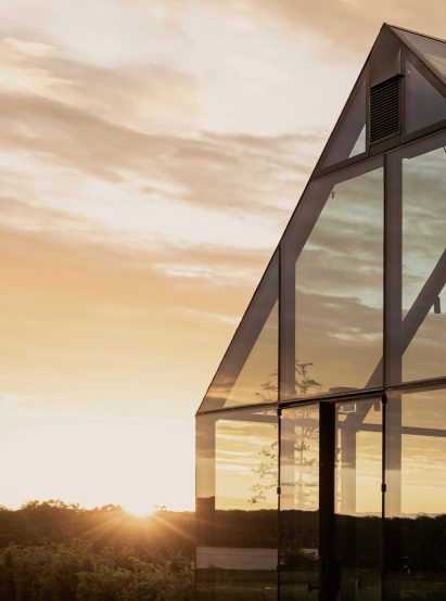 Glass panels surrounding steel frame of Swedish restaurant in meadow