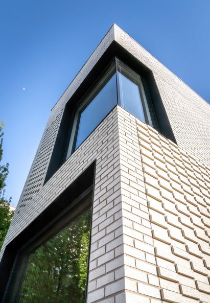 White brick house with large glass windows by Gradient Architecture