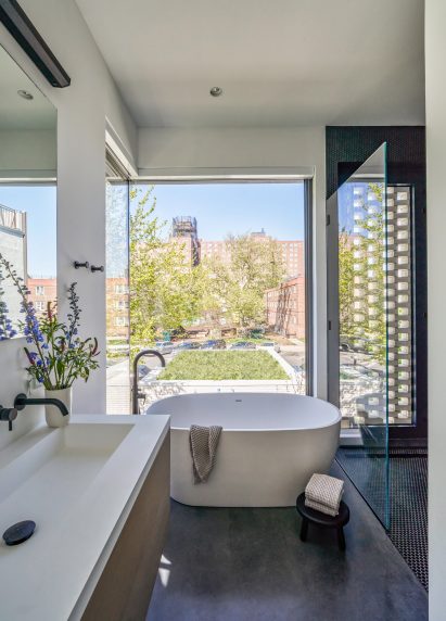 Ensuite bathroom with large window and white bathtub in New York City