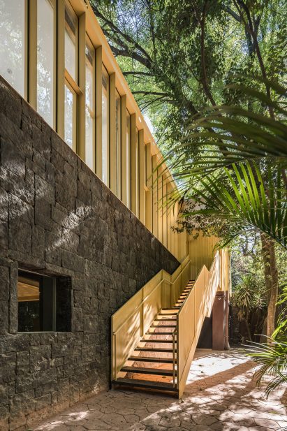Yellow steel stairway leading up stone building with new pavilion on top