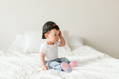 A baby sitting on a bed wearing pink and blue shoes
