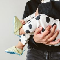 A baby wearing green Woolybubs shoes