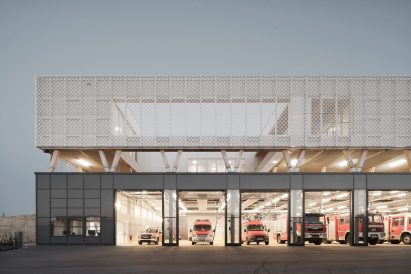 Fire station with perforated metal-clad upper storey on concrete podium