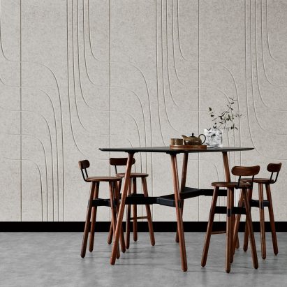Wooden table and chairs in front of wall panel with undulating pattern