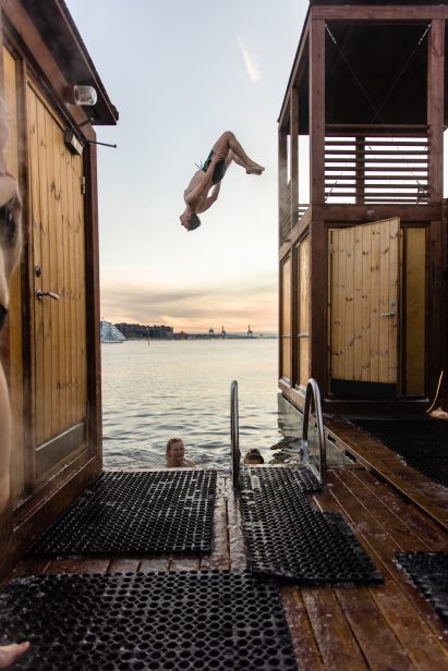 Man doing flip over harbour from timber diving tower