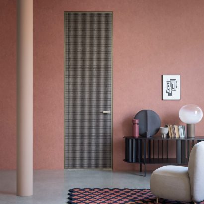 Wooden door with bronze outline in a pink-painted room
