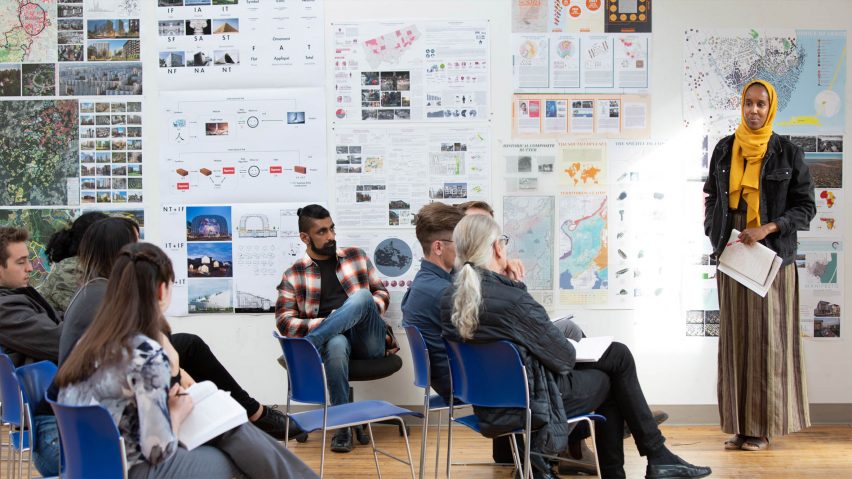 Person standing in front of an architectural presentation speaking to an audience